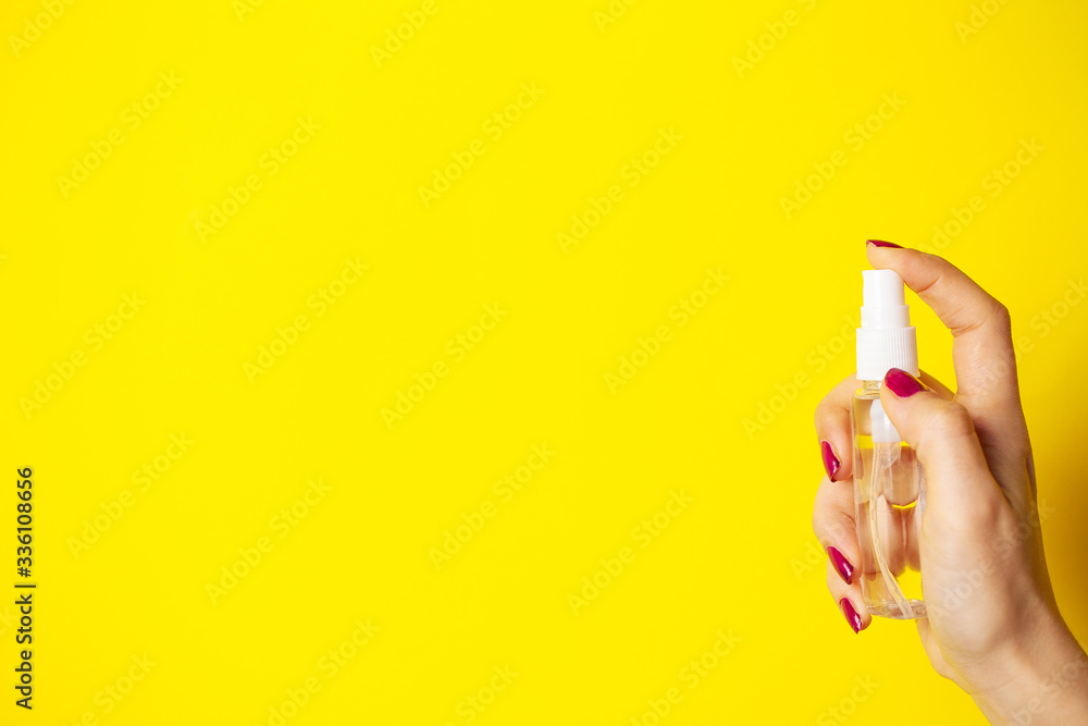 A woman uses antiseptic on yellow background A woman uses antiseptic on yellow background