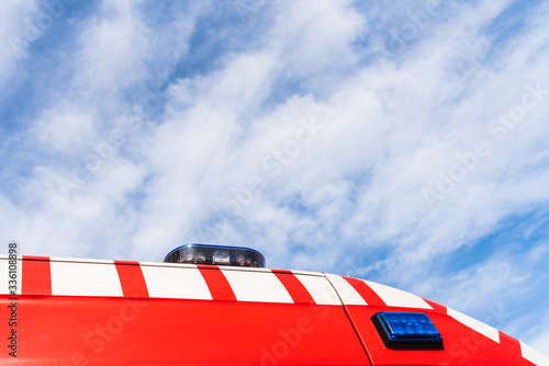 Red roof of a medicalized ambulance over blue sky with clouds and copy space, to care for pandemic sufferers. photo