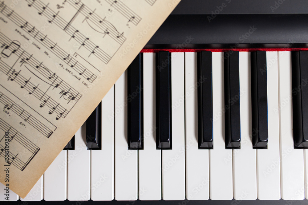 Fototapeta premium Piano and vintage music sheets close up