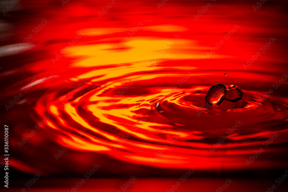 Wasser tropfen auf wasser rot Hintergrund beleuchtung mit kleinen wellen Wasser tropfen auf wasser rot Hintergrund beleuchtung mit kleinen wellen