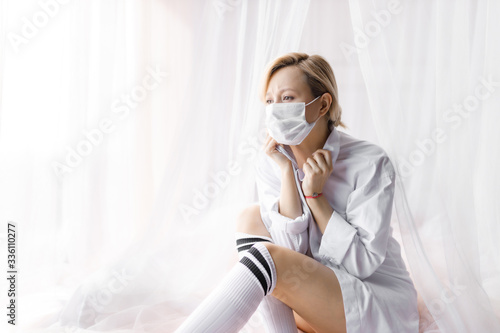 Disease of the girl in home quarantine. A girl in protective medical masks sits on a bed. Virus protection, coronavirus pandemic, epidemic prevention.