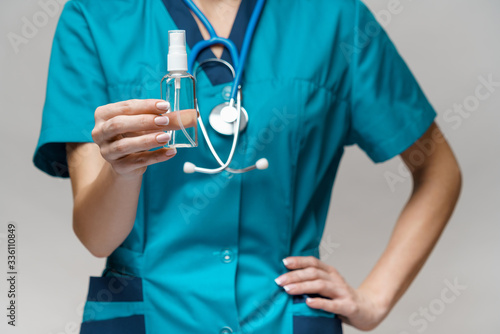 medical doctor nurse wearing protective mask - holding bottle of sanitizing spray or gel