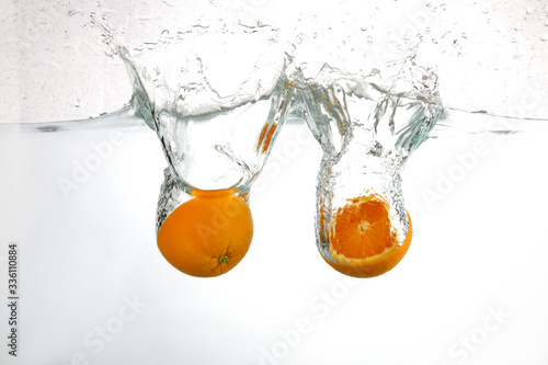 oranges splashing through the water isolated on white background.