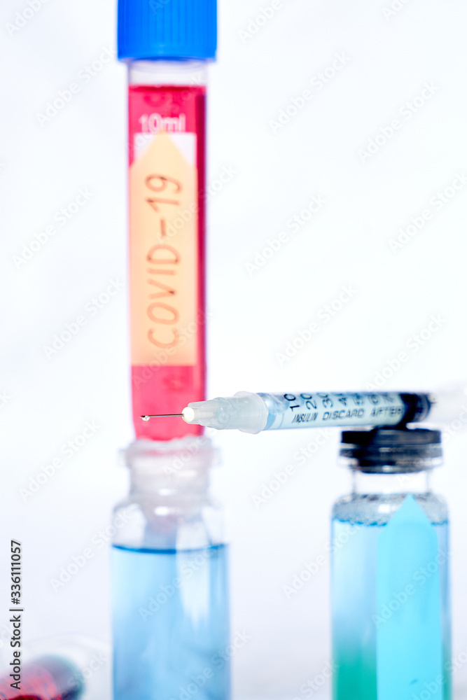 A syringe for injection with a coronavirus vaccine, antiviral tablets and 2 syringes with red and yellow liquids on a white background A syringe for injection with a coronavirus vaccine, antiviral tablets and 2 syringes with red and yellow liquids on a white background