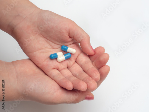 woman's hand holding blue and white tablets. self-medication during coronavirus