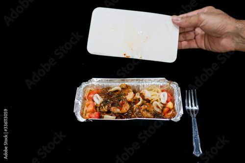 Delivery Spaghetti, Spaghetti with spicy mixed seafood in freeware tray take home on black background, Delicious spaghetti with spicy mixed seafood served on plate, Italian food, Open box.