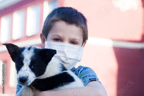 Young boy wear protection mask and holding puppy outdoors. To prevent pathogens caused by sick dog. Health care with pet and natural. Covid-19 virus.