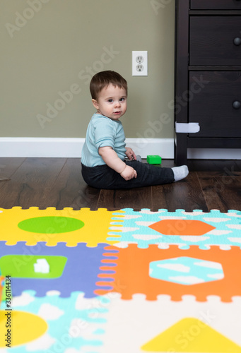 Baby boy sitting near baby proofed electrical outlets and drawers