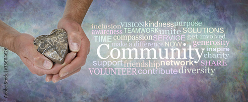 Care for your Community Word Cloud - male  hands holding a wooden rustic heart with the word CARE beside a COMMUNITY word cloud against a rustic stone effect blue grey  background 
