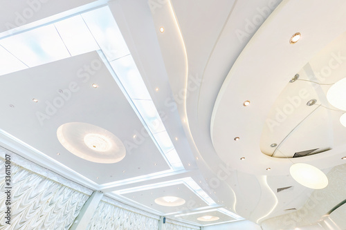 suspended ceiling with halogen spots lamps and drywall construction in empty room in apartment or house. Stretch ceiling white and complex shape. photo