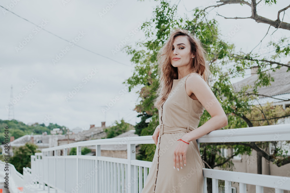 beautiful fashionable woman in a beige dress in the park on a walk