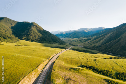 Road in green valley of Altai Mountains at sunset. Summer nature landscape in Altai Republic, Siberia, Russia