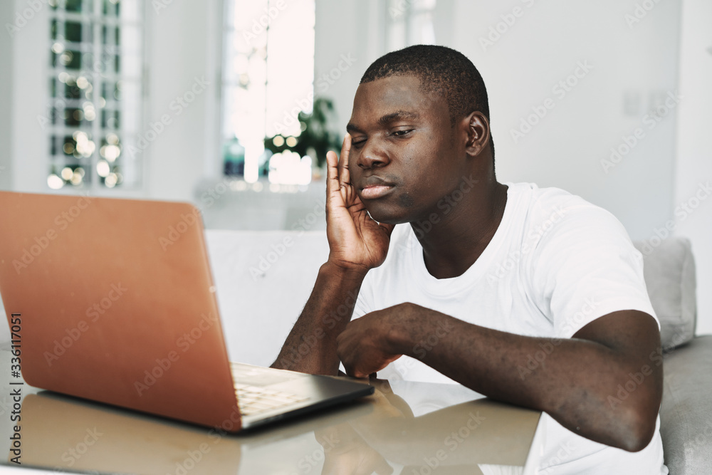 A man of African appearance at home in front of a laptop relaxing A man of African appearance at home in front of a laptop relaxing