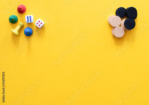 Chess pieces, game chips, Lotto barrels, draughts and playing cubes are laid on a yellow background: entertainment, games at home for the whole family, the concept of table games