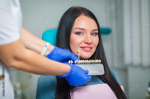 Closeup of a girl with beautiful smile at the dentist. Dental. Dentist matching teeth colour in office. Beautiful Model Girl with white teeth and perfect skin. Teeth whitening.