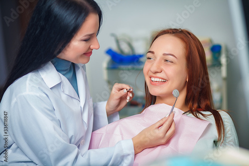 Young beautiful woman with beautiful white teeth sitting on a dental chair. Portrait of a woman with toothy smile sitting during examination at the dental office