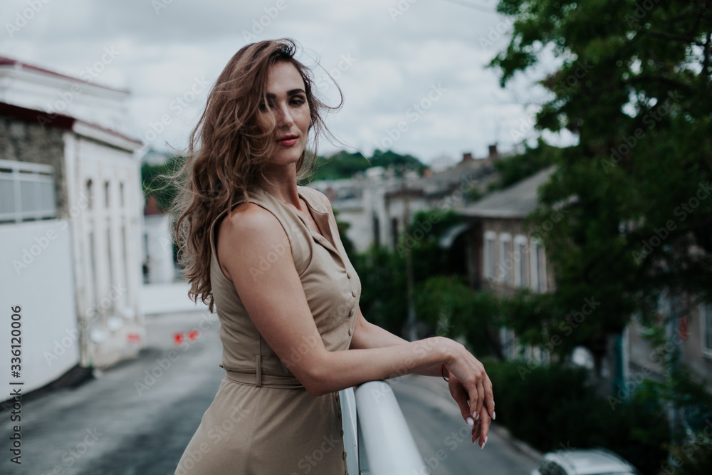 Fototapeta premium beautiful fashionable woman in a beige dress in the park on a walk