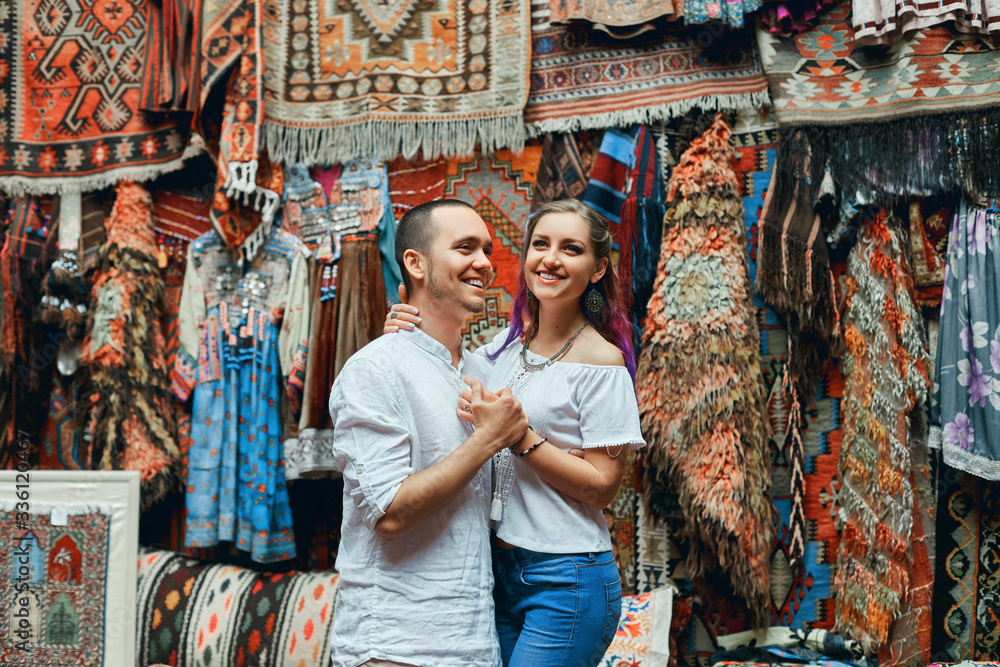 Obraz premium Couple in love walks and hugs at the Eastern carpet market. A man and a woman choose a Turkish carpet