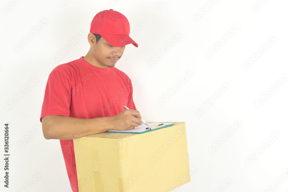 Delivery services concept. young delivery man holding box and writing something on clipboard. Delivery services concept. young delivery man holding box and writing something on clipboard.