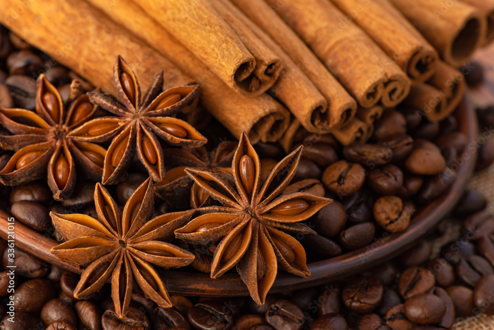 Stars of anise, coffee beans in a saucer and cinnamon sticks close - up in brown tones. Stars of anise, coffee beans in a saucer and cinnamon sticks close - up in brown tones.