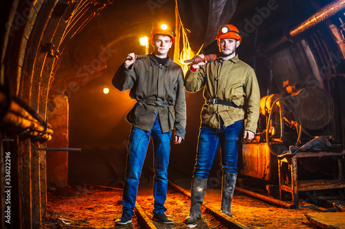 Miners in the process of working with tools in their hands. Coal mine. Two miners in the mine. Copy Space