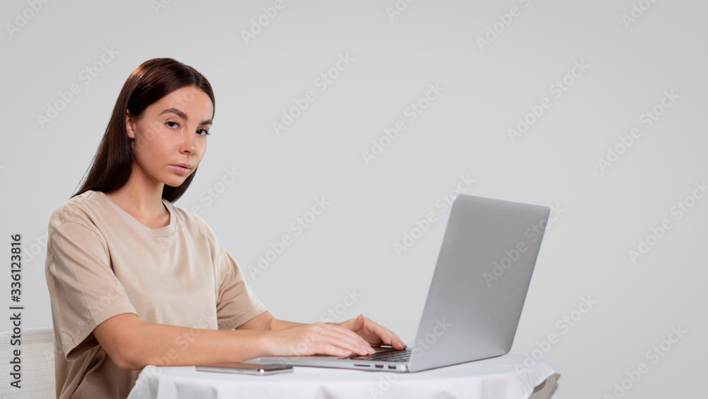 Mid shot of pretty female, she seats at the table and works freelance at her home computer, isolated over white Mid shot of pretty female, she seats at the table and works freelance at her home computer, isolated over white