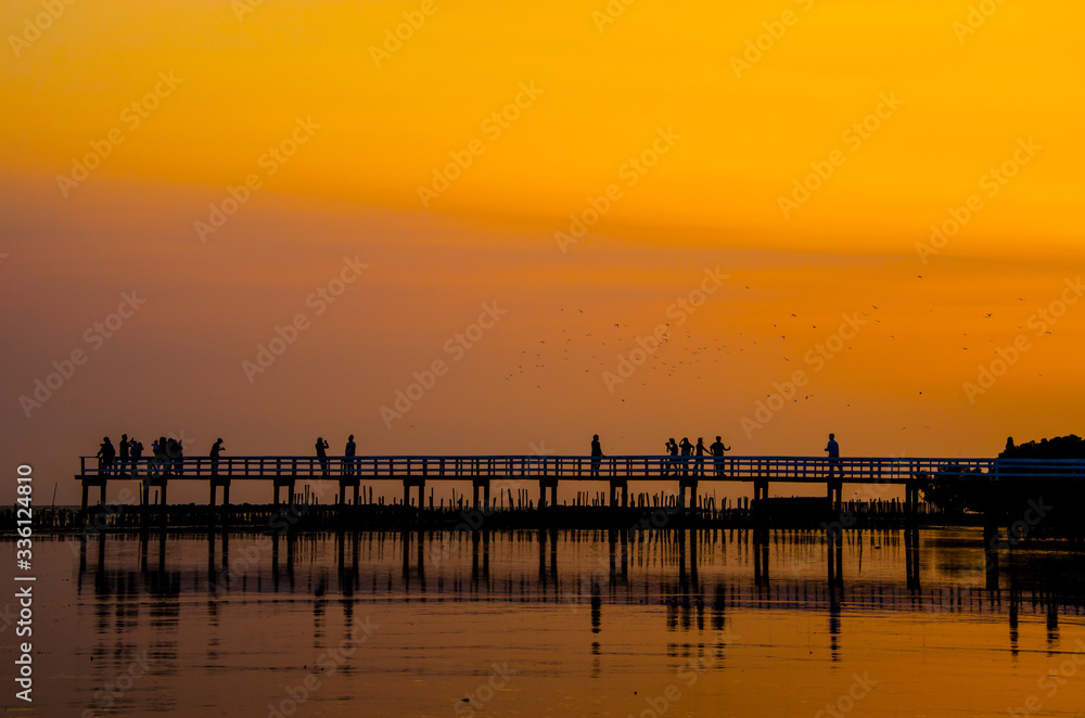 Wooden bridge and people against the sunset sky background