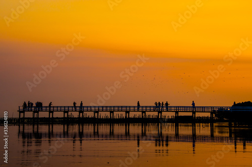 Wooden bridge and people against the sunset sky background