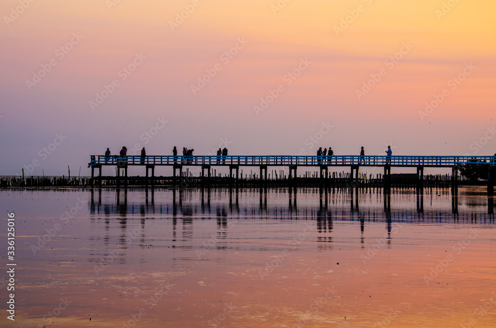 People walking on a wooden bridge against the sunset sky background, silhouette image