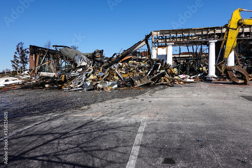 A one story building with white columns destroyed by fire full of debris