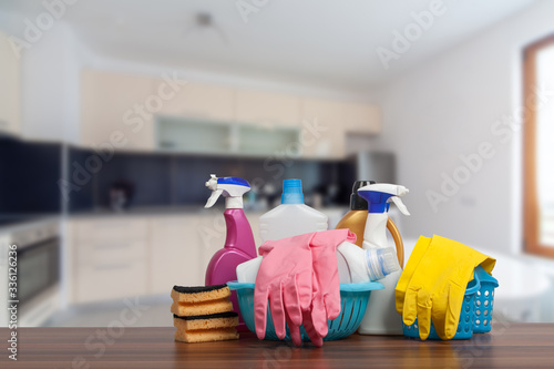 Home cleaning service concept with supplies. Close up of cleaning supplies in front of kitchen. photo