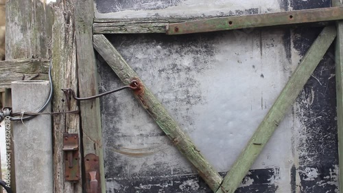 The man closes the fence with his hand. Close-up. Man in uniform closes the door of the gate of his house.