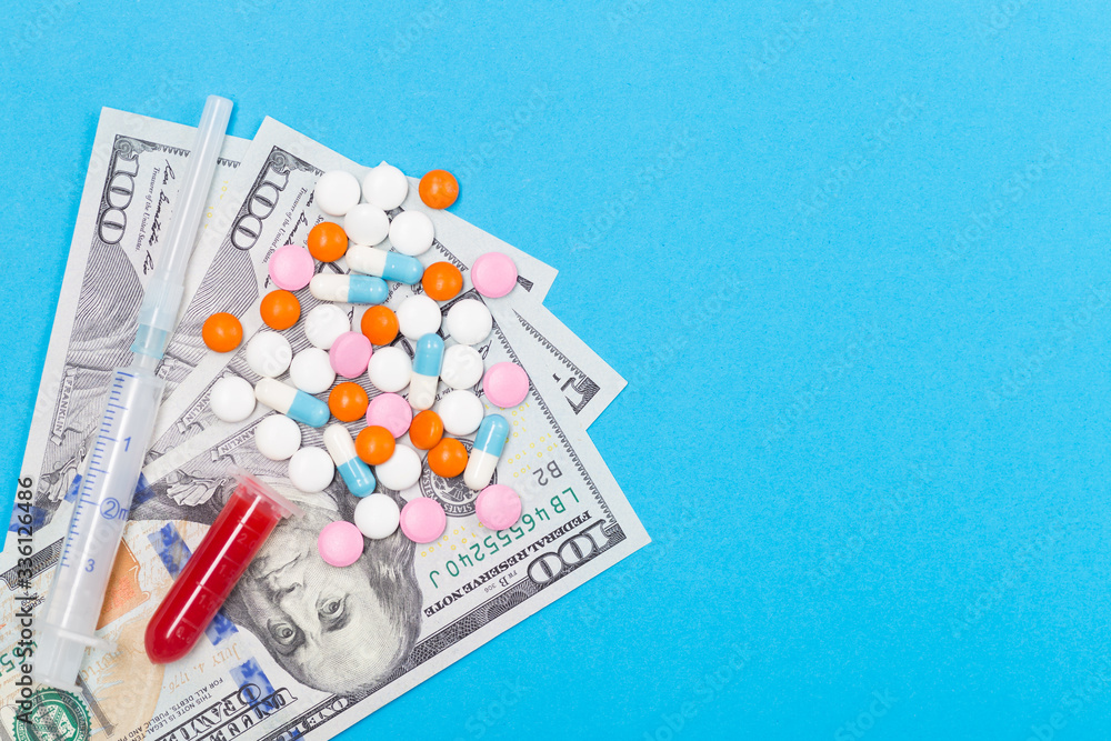 Medicine pills, syringe, blood test tube, tablets and capsules on US dollars background. Free space. Healthcare concept Medicine pills, syringe, blood test tube, tablets and capsules on US dollars background. Free space. Healthcare concept