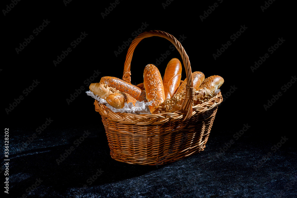 Fresh rolls in basket on dark background. Poppy seed roll and sesame seed roll. Typical popular czech breakfast rolls or buns.