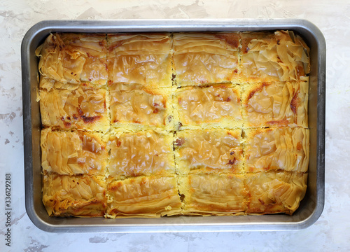 Concetto di cucina greca. Bougatsa greco tradizionale casalingo, pasta fillo riempita di crema su fondo bianco. Vista dall'alto.