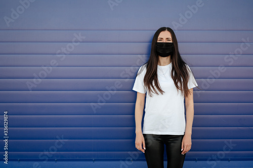 Woman wearing face mask because of Air pollution or virus epidemic in the city. Оn a blue background. Corona virus concept. © Ярослав Поляков