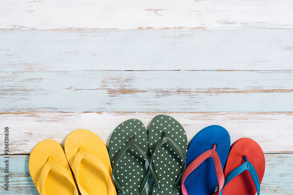 Colorful slippers on old wooden board with free space. Travel and summer concept.