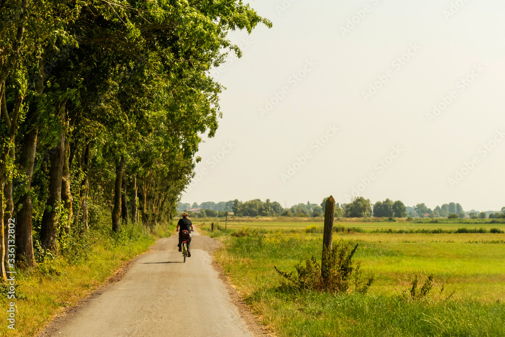 Rural landscape in West Flanders, Belgium near Beveringe with a cycling tourist 