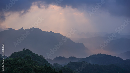 A stunning sunrise over the mountains in China with golden and blue/purple colours, covered by forest and jungles 