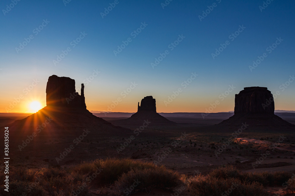 The sun rising on the background of The Mittens and Merrick Butte from John Wayne's Point the Oljato Navajo Monument Valley, Arizona USA The sun rising on the background of The Mittens and Merrick Butte from John Wayne's Point the Oljato Navajo Monument Valley, Arizona USA
