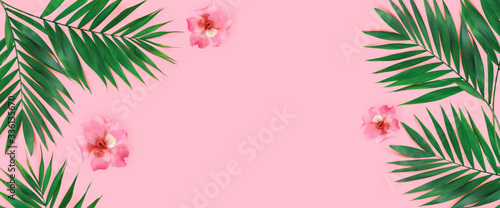 Creative flat lay top view of green tropical palm leaves with flowers  on pink paper background.
