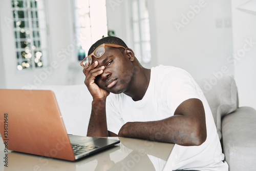 A man of African appearance at home in front of a laptop relaxing.