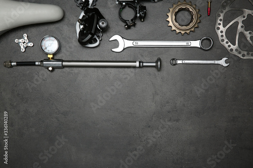 Set of different bicycle tools and parts on grey stone table, flat lay. Space for text