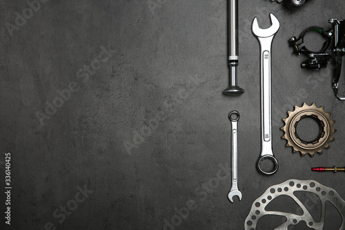 Set of different bicycle tools and parts on grey stone table, flat lay. Space for text photo