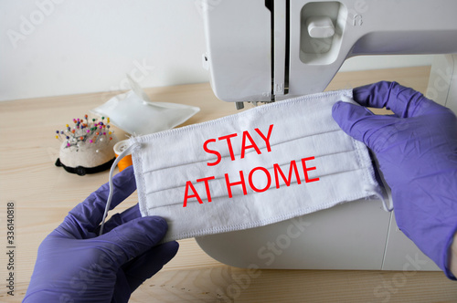 Hands with purple gloves holding protection mask with sign Stay at home, quarantine, corornavirus. photo