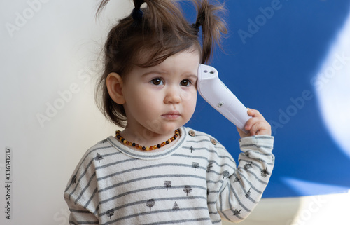 Baby girl holding electronic thermometer and check out temperature hersself. photo