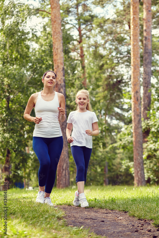 running sporty mother and daughter. woman and child jogging in a park. outdoor sports and fitness family.