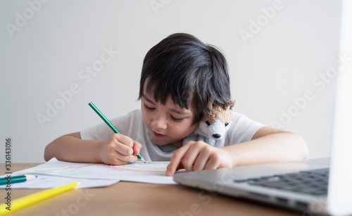 Happy kid having fun watching cartoon on tablet, Child using digital pad searching the ideas on internet for his drawing art homework, Home schooling, Social Distancing, E-learning online education