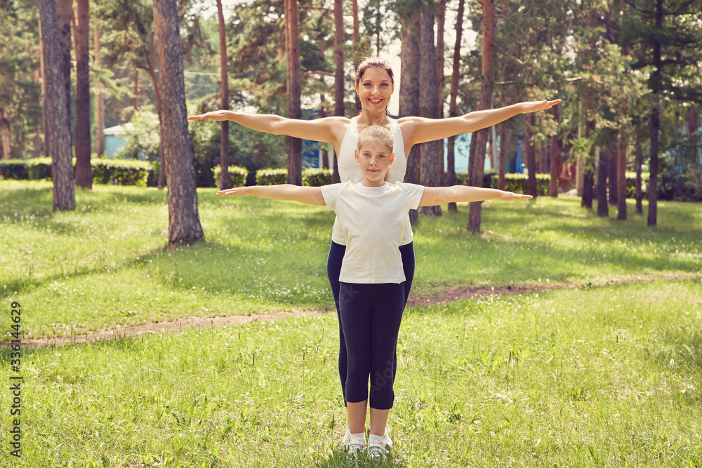 sporty mother and daughter. woman and child training in a park. outdoor sports and fitness family.