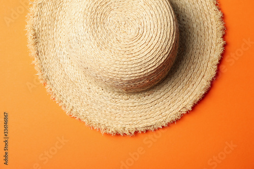 Straw hat on orange background, top view